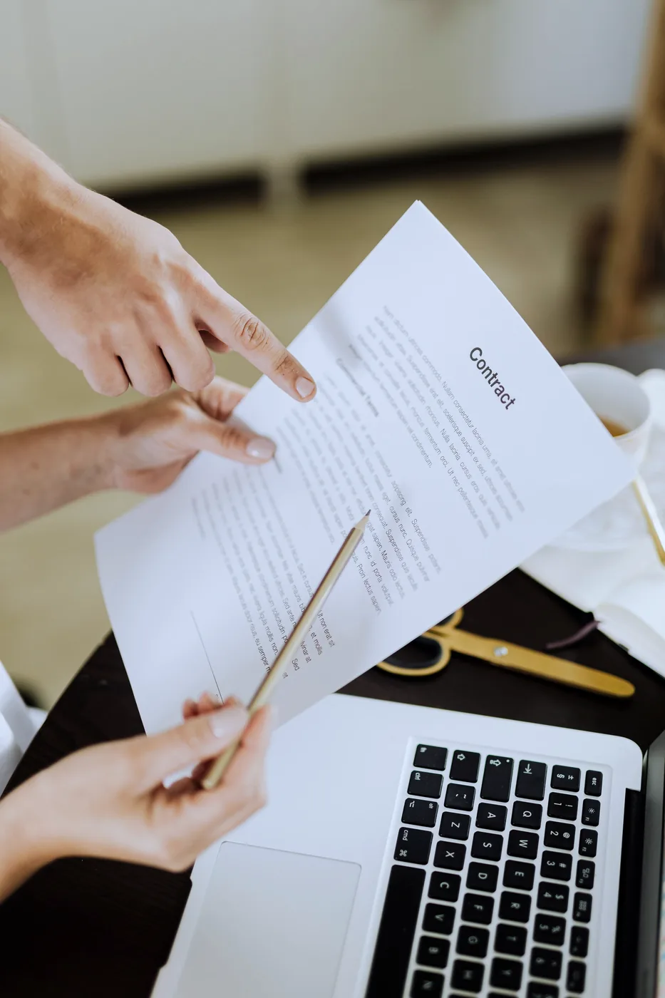 Hands reviewing contract terms over a laptop